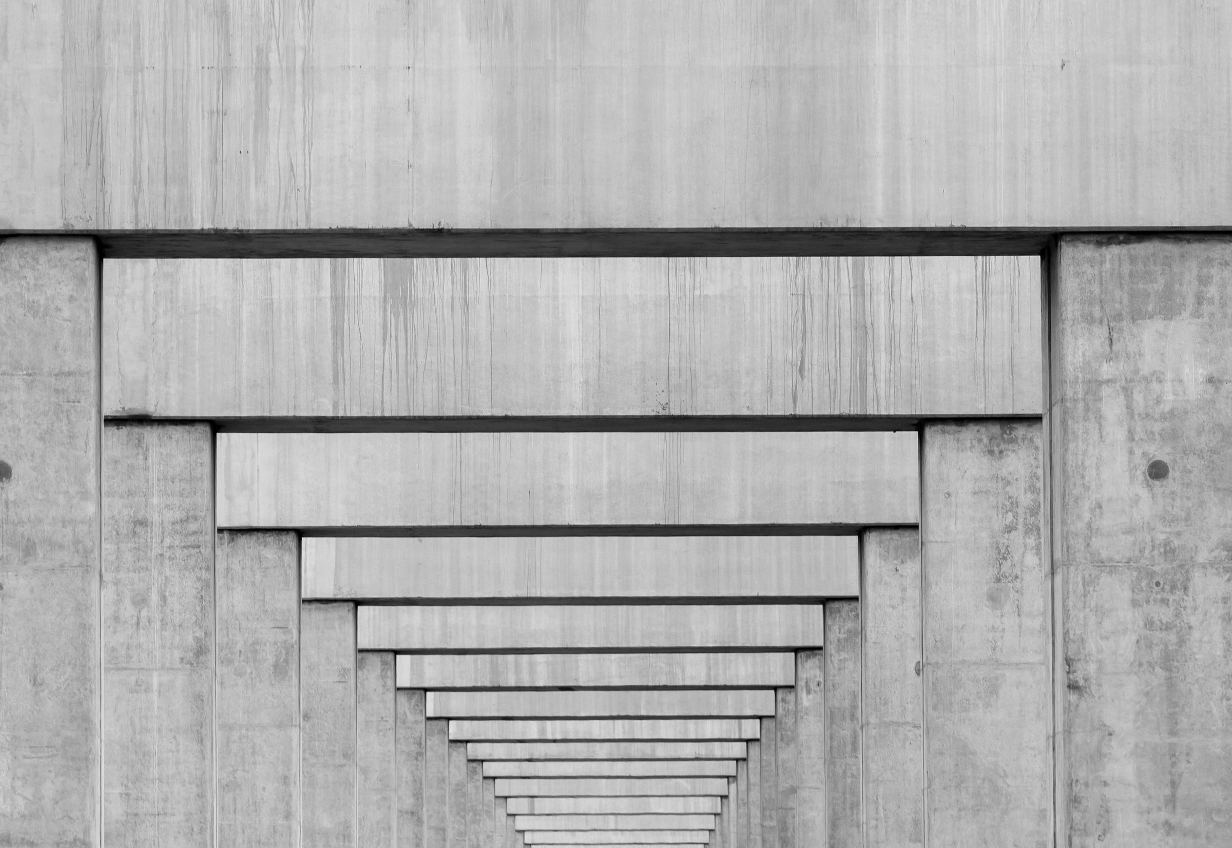 A stepped concrete recession receding toward a vanishing point — representing structural depth and precision.
